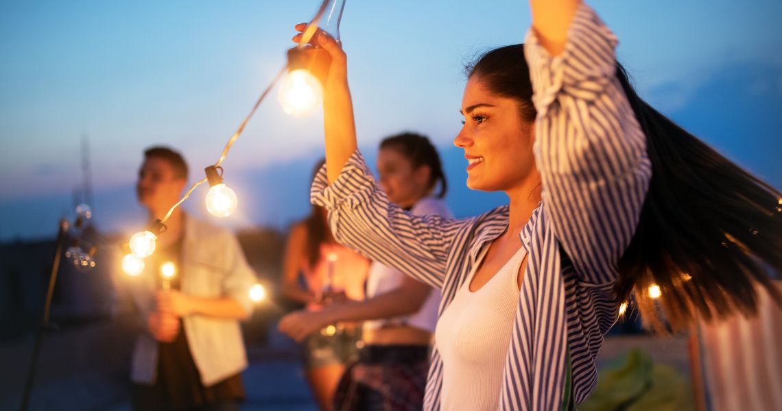 events-moon-dinner-3 Woman stringing up lights at a nightime palacios event.