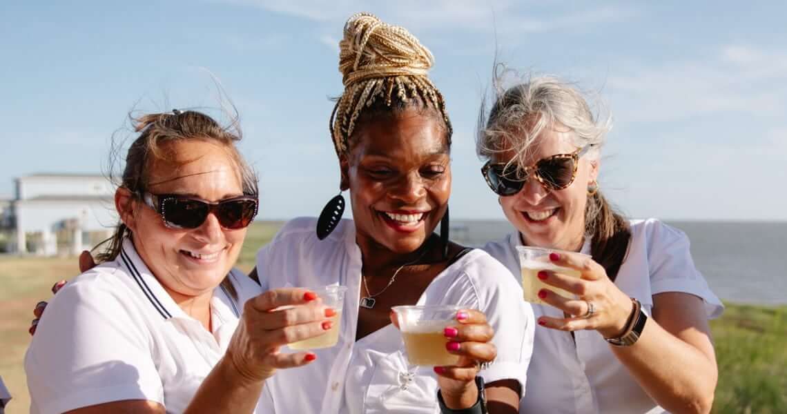 Three women celebrating with a drink