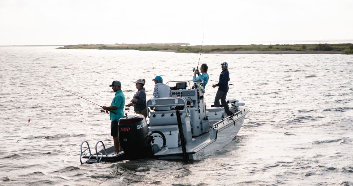 A group of people enjoying a fishing trip on a boat in a coastal area.