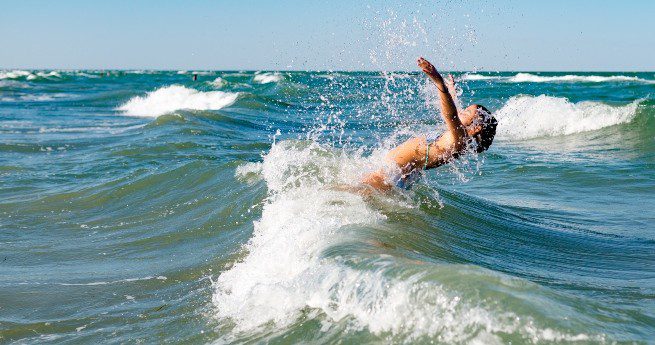 complete guide to visiting matagorda bay nature park-swimming-4 The image captures a person enjoying the ocean waves, with their body arched backward as they splash into the water.